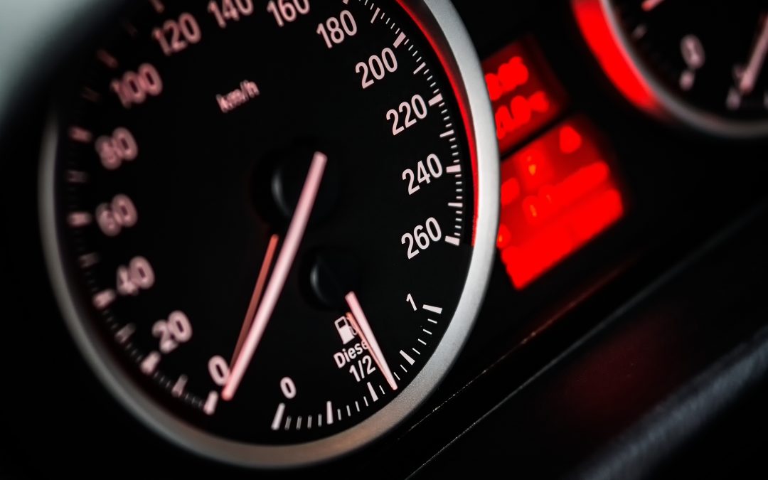 Close-up of a car speedometer and fuel gauge with illuminated dials and red dashboard lights, highlighting the importance of a local smog check for optimal performance.